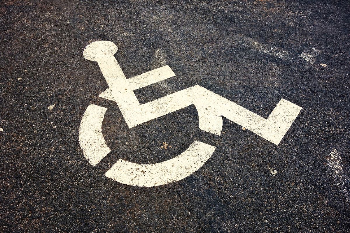 Symbol wózka inwalidzkiego namalowany na asfaltowej drodze.